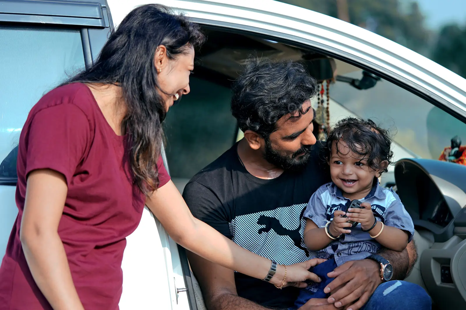 A family with a small child sitting in the front of a car